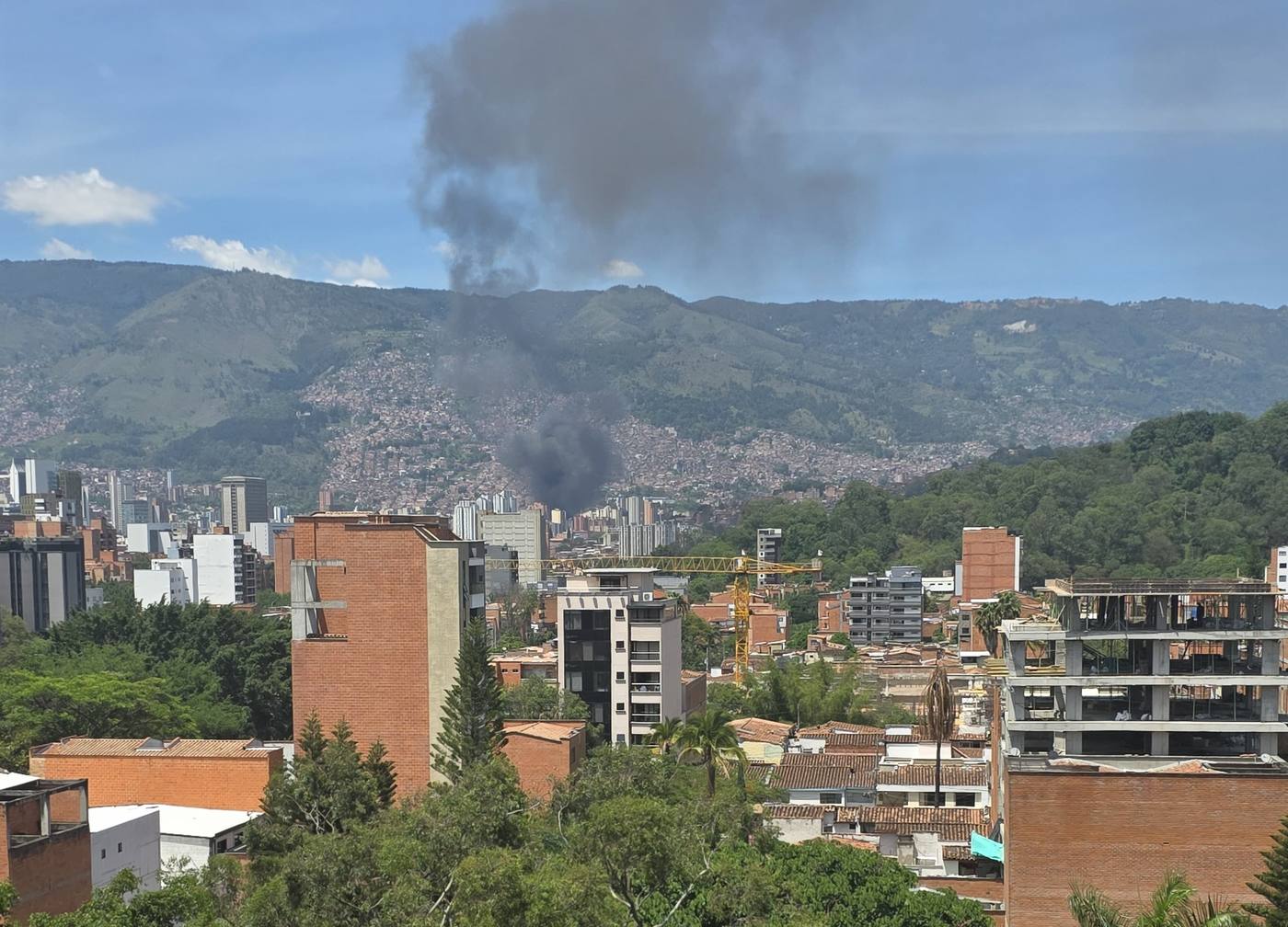 A column of black smoke rising from the hillside neighborhoods of Medellín